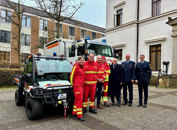Innensenator Ulrich Mäurer zwischen DLRG und Feuerwehr vor den neuen Fahrzeugen