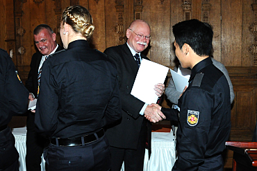 Foto: Innensenator Mäurer (Mitte) überreicht einem Absolventen des Studiengangs Polizeivollzugsdienst (HfÖV) das Abschlusszeugnis